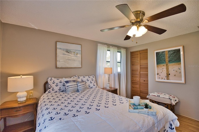 bedroom with wood-type flooring, a textured ceiling, a closet, and ceiling fan