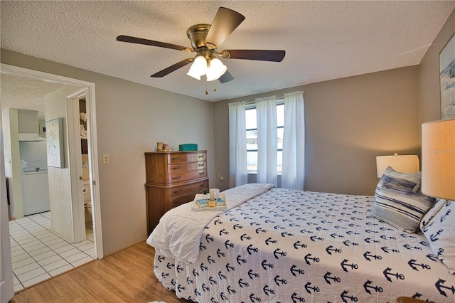 bedroom with ceiling fan, light hardwood / wood-style floors, a textured ceiling, and connected bathroom