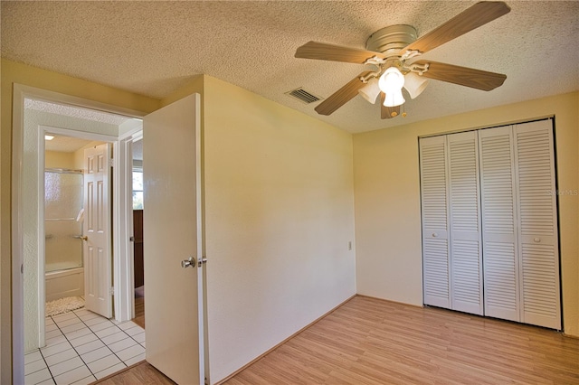 unfurnished bedroom featuring ceiling fan, a closet, light hardwood / wood-style floors, and a textured ceiling