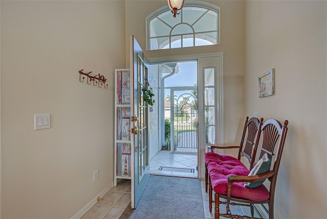 foyer featuring a towering ceiling, a healthy amount of sunlight, and light tile patterned floors