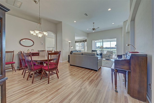 dining space featuring light hardwood / wood-style floors and ceiling fan with notable chandelier