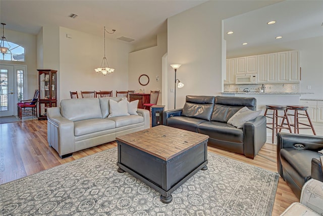 living room featuring a chandelier, light hardwood / wood-style flooring, and french doors