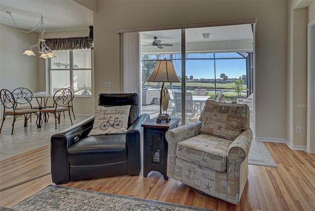 living area featuring ceiling fan with notable chandelier and light wood-type flooring