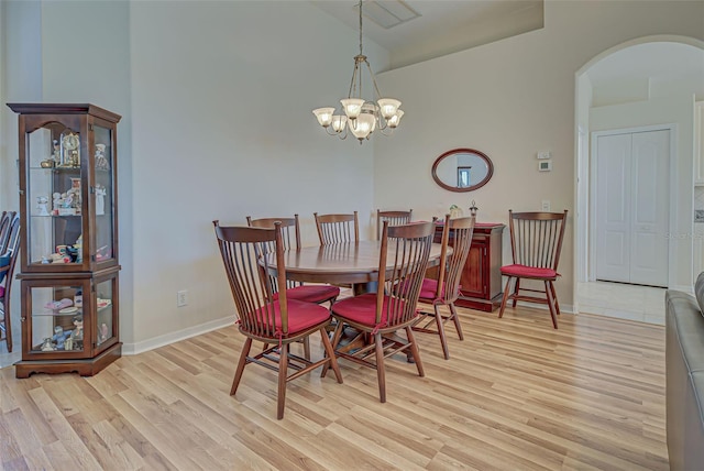 dining area with vaulted ceiling, a chandelier, and light hardwood / wood-style floors