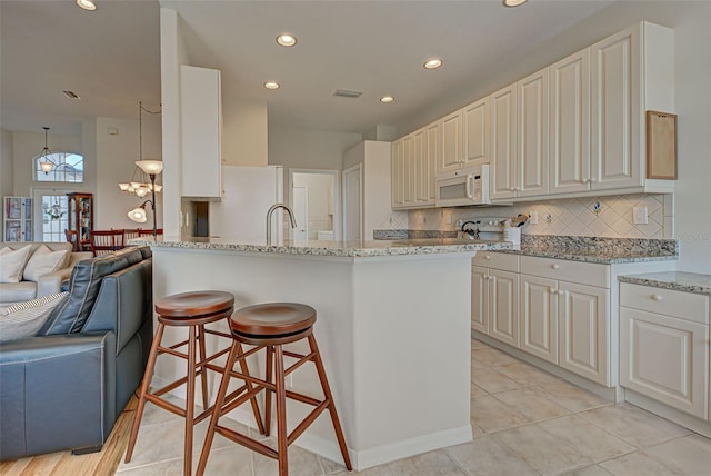 kitchen featuring white appliances, decorative backsplash, light tile patterned floors, and light stone countertops