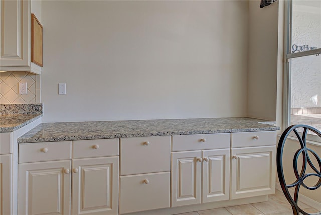 interior space featuring light stone counters, white cabinets, and tasteful backsplash