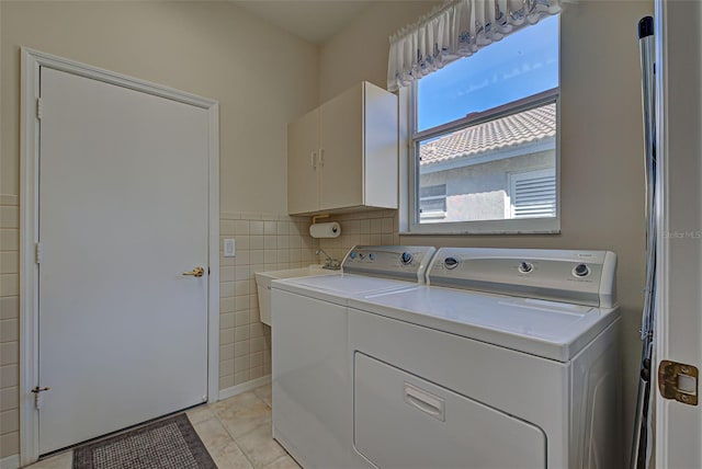 laundry room featuring cabinets, sink, tile walls, independent washer and dryer, and light tile patterned floors