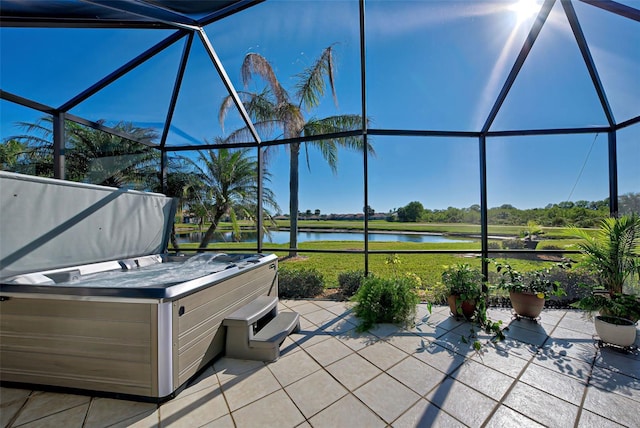 view of patio / terrace featuring a lanai, a hot tub, and a water view