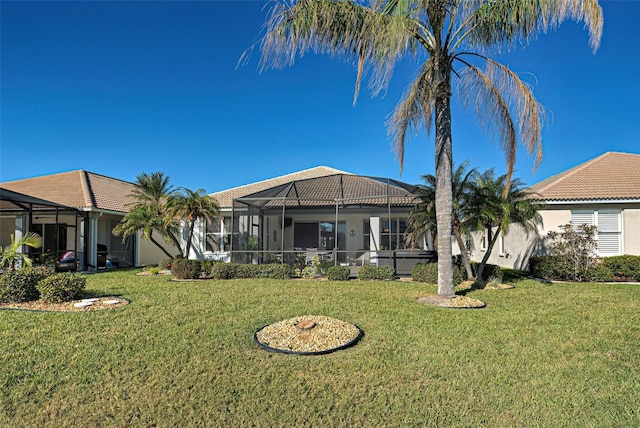 rear view of property with glass enclosure and a yard