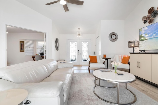 living room with ceiling fan with notable chandelier, french doors, light wood-type flooring, and a healthy amount of sunlight