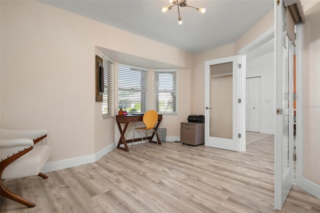 sitting room with a chandelier, french doors, and light wood-type flooring