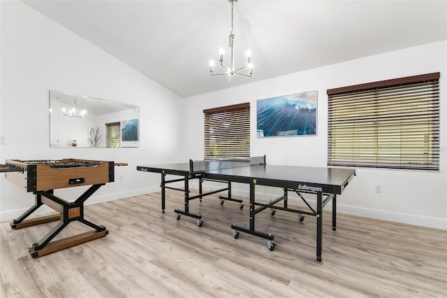 playroom with a wealth of natural light, light hardwood / wood-style flooring, lofted ceiling, and a notable chandelier