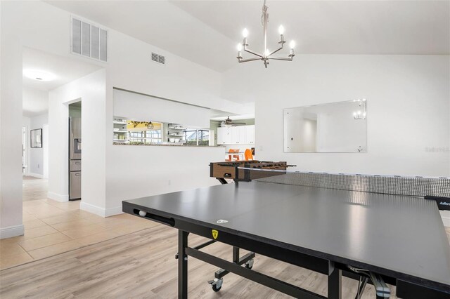 playroom featuring vaulted ceiling, light hardwood / wood-style flooring, and ceiling fan with notable chandelier