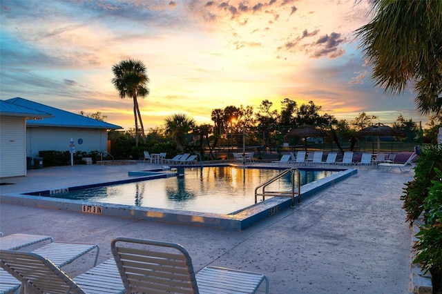 pool at dusk featuring a patio area