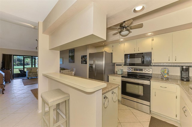 kitchen featuring a kitchen breakfast bar, kitchen peninsula, light tile patterned floors, and appliances with stainless steel finishes