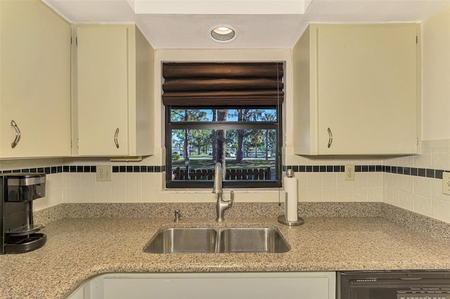 kitchen with decorative backsplash, light stone counters, and sink