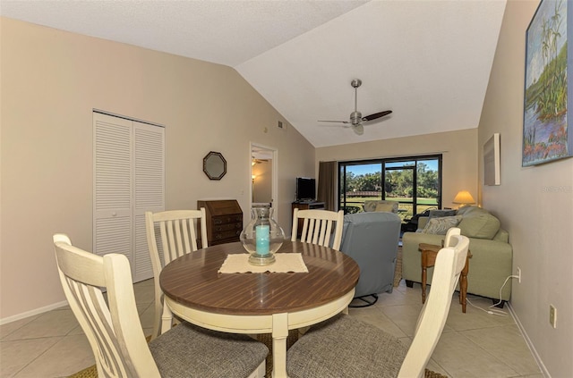 dining space with ceiling fan, light tile patterned flooring, and vaulted ceiling