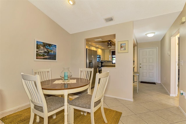 tiled dining room with ceiling fan, lofted ceiling, and a textured ceiling