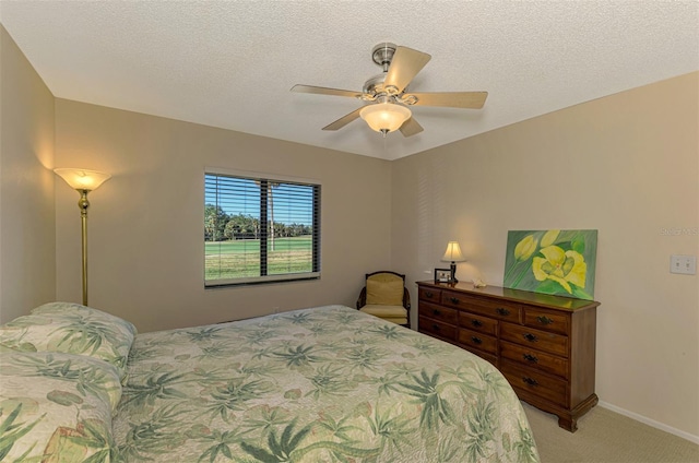 carpeted bedroom featuring ceiling fan and a textured ceiling