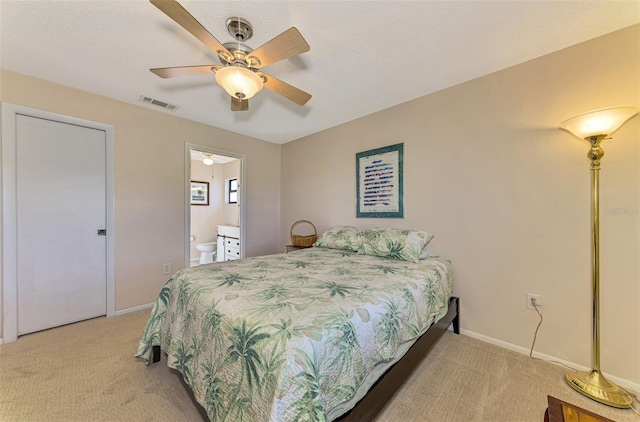 carpeted bedroom featuring a textured ceiling, ensuite bath, and ceiling fan