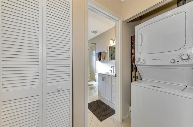 washroom with stacked washer / dryer, sink, and light tile patterned floors