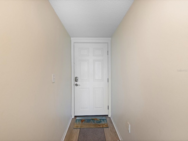 doorway with lofted ceiling, hardwood / wood-style floors, and a textured ceiling