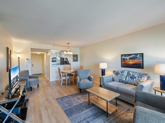 living room with a textured ceiling, light hardwood / wood-style flooring, and a notable chandelier