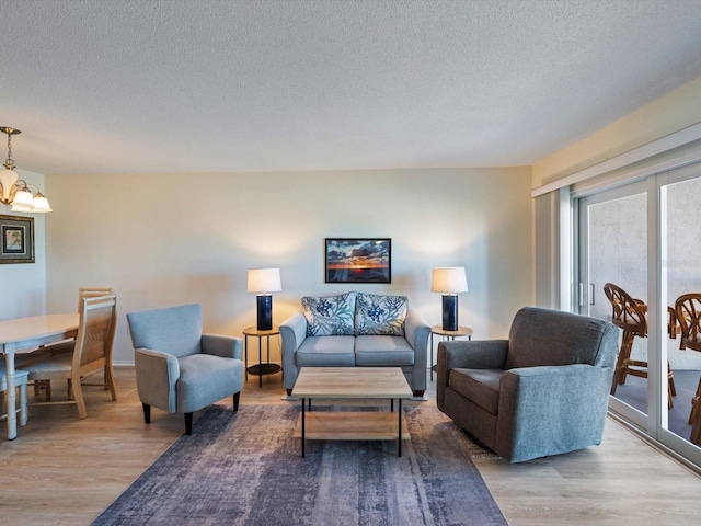 living room featuring a textured ceiling, light hardwood / wood-style flooring, and a notable chandelier