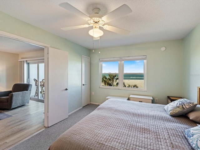 bedroom with a textured ceiling, light wood-type flooring, multiple windows, and ceiling fan