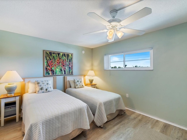 bedroom with ceiling fan, light hardwood / wood-style flooring, and a textured ceiling