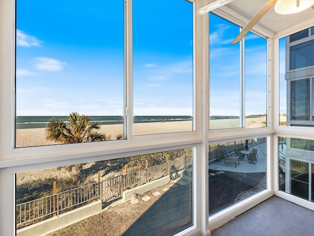 unfurnished sunroom with a water view and a beach view