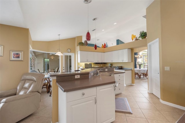 kitchen featuring a kitchen island with sink, white cabinets, sink, hanging light fixtures, and light tile patterned flooring