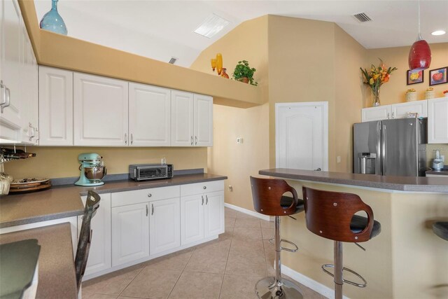 150 Marker Rd, Rotonda West, FL 33947 - kitchen with stainless steel refrigerator with ice dispenser, a kitchen bar, dark countertops, white cabinetry, and light tile patterned floors