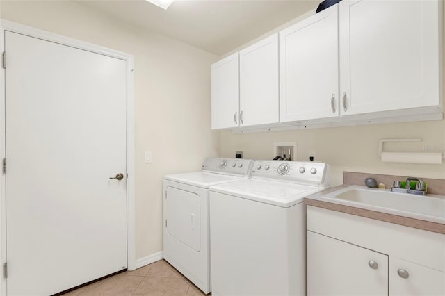 laundry room with cabinets, light tile patterned floors, separate washer and dryer, and sink