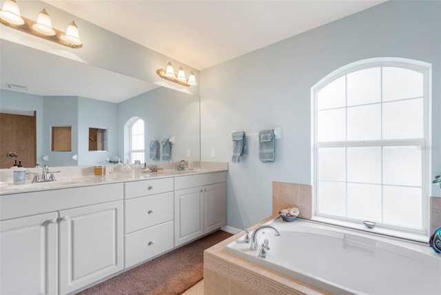 bathroom with vanity and tiled tub