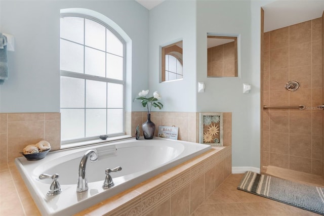 bathroom with a relaxing tiled tub and tile patterned floors