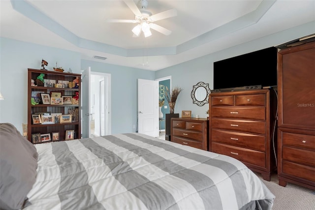 bedroom featuring light carpet, a tray ceiling, and ceiling fan