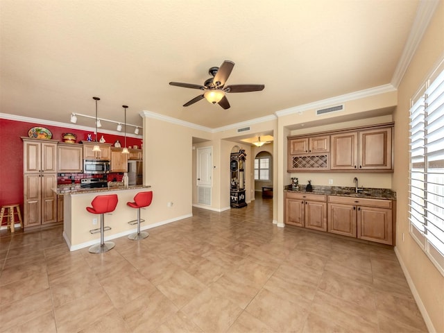 kitchen featuring sink, crown molding, hanging light fixtures, a kitchen bar, and stainless steel appliances