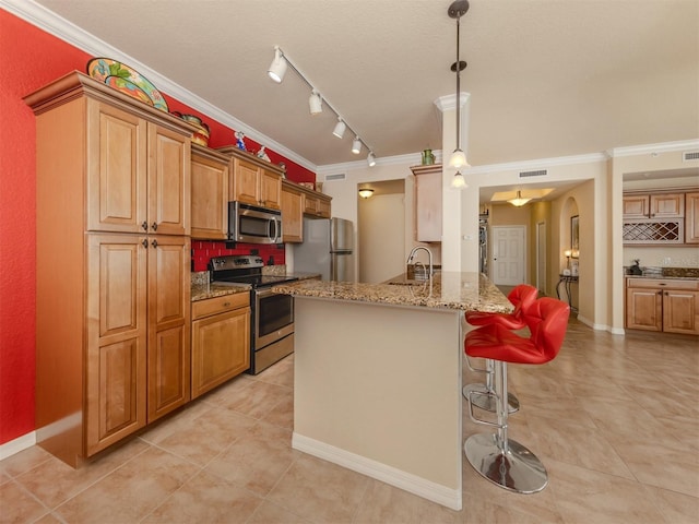 kitchen with kitchen peninsula, appliances with stainless steel finishes, a kitchen breakfast bar, ornamental molding, and pendant lighting