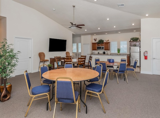 carpeted dining space with high vaulted ceiling and ceiling fan