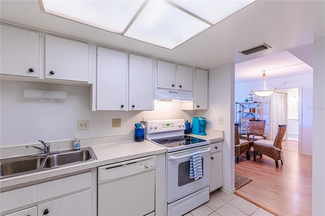 kitchen featuring decorative light fixtures, white appliances, sink, and light hardwood / wood-style flooring