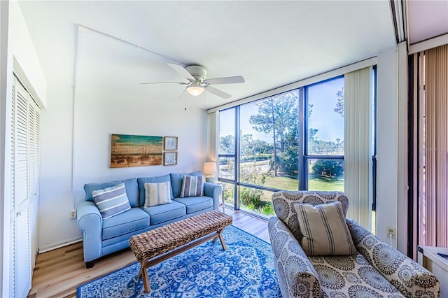 living room with light hardwood / wood-style floors, a wall of windows, and ceiling fan