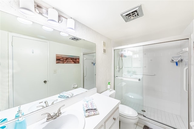 bathroom featuring tile patterned flooring, vanity, a shower with shower door, and toilet