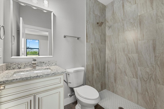 bathroom with vanity, tiled shower, and toilet