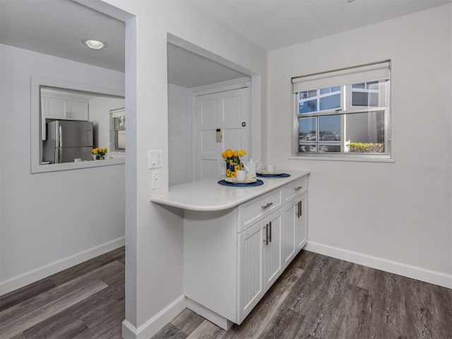 kitchen with dark hardwood / wood-style flooring, white cabinetry, and stainless steel refrigerator