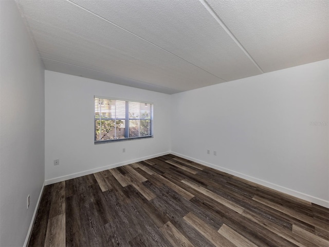 empty room featuring a textured ceiling and dark hardwood / wood-style flooring