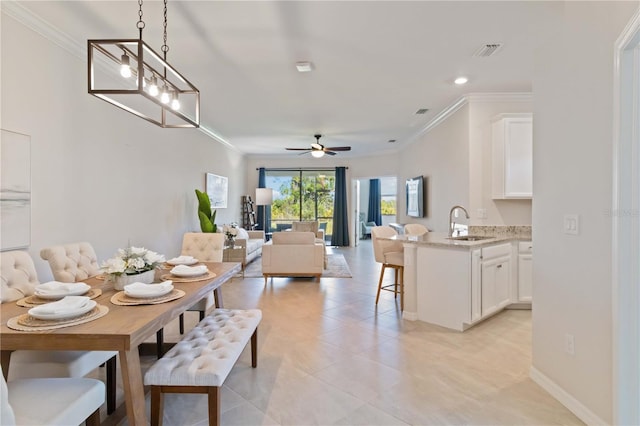 dining space with ceiling fan, crown molding, and sink