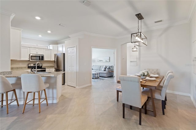 dining space with sink, light tile patterned floors, and ornamental molding