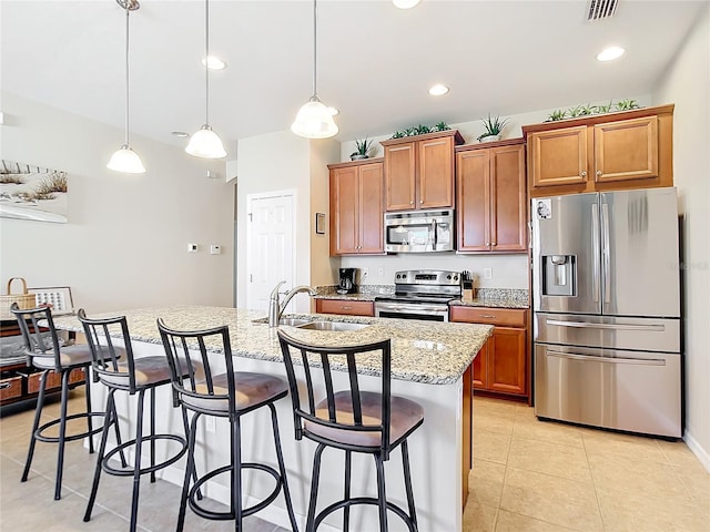 kitchen with a center island with sink, decorative light fixtures, sink, and stainless steel appliances