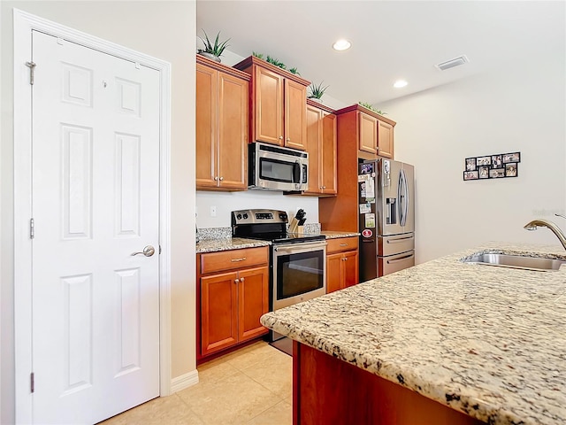 kitchen with light tile patterned flooring, light stone countertops, sink, and appliances with stainless steel finishes